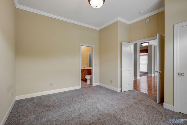 unfurnished bedroom with baseboards, ensuite bathroom, crown molding, and light colored carpet