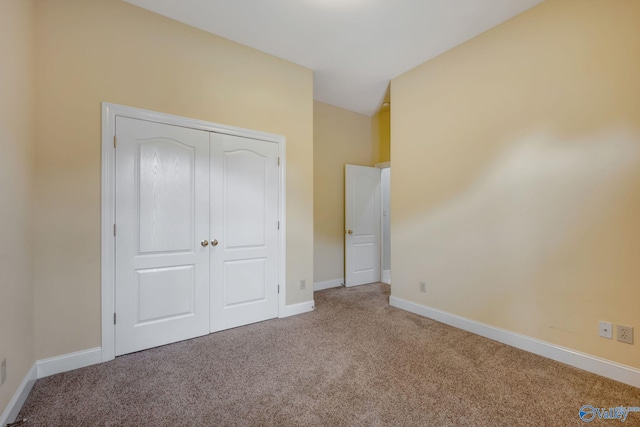 unfurnished bedroom featuring carpet floors, baseboards, and a closet