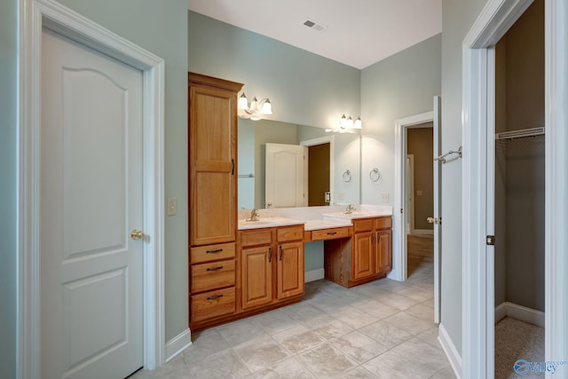 bathroom with double vanity, a sink, visible vents, and baseboards