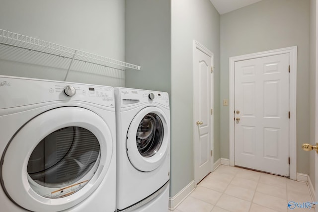 laundry area with baseboards, laundry area, light tile patterned flooring, and washer and dryer