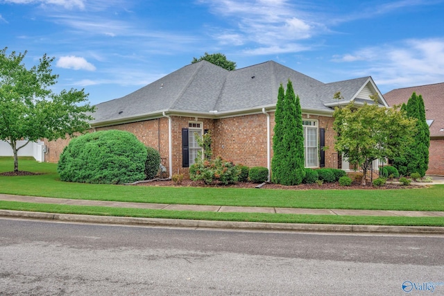 view of front of property with brick siding, roof with shingles, and a front yard