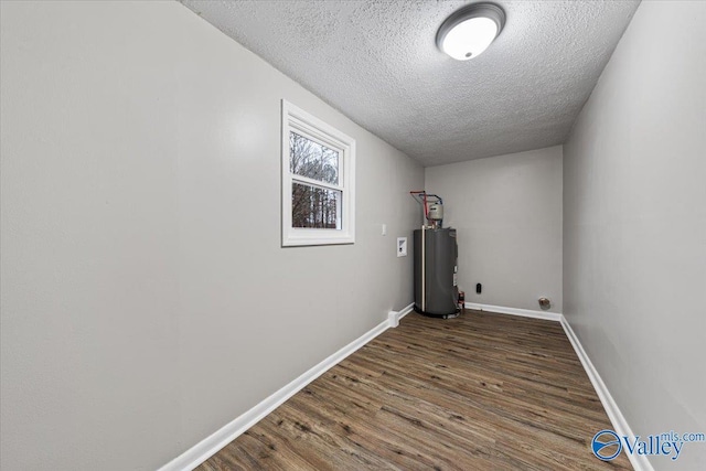 laundry room featuring dark hardwood / wood-style floors, electric water heater, and a textured ceiling