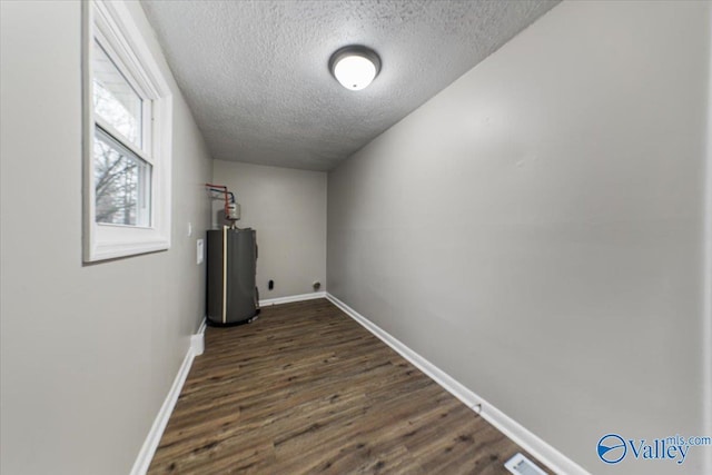 washroom with water heater, a textured ceiling, and dark hardwood / wood-style flooring