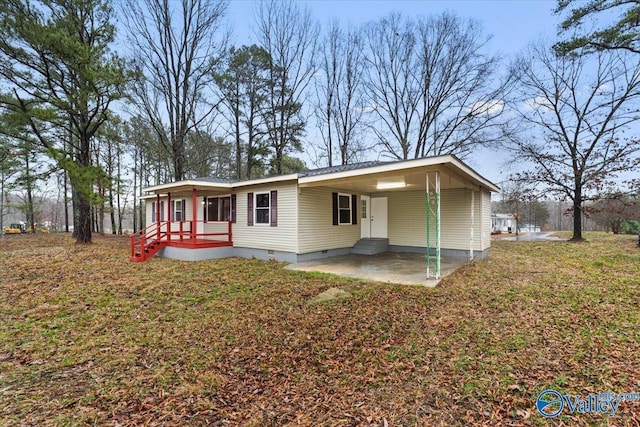 back of house featuring a lawn, a carport, and a patio area