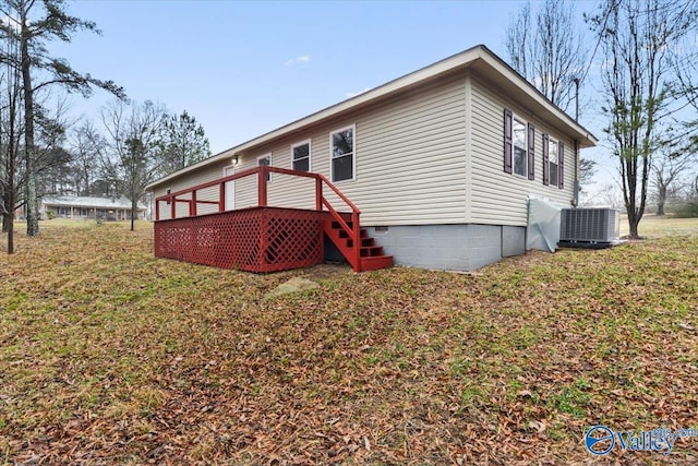 exterior space with a wooden deck, a lawn, and central air condition unit