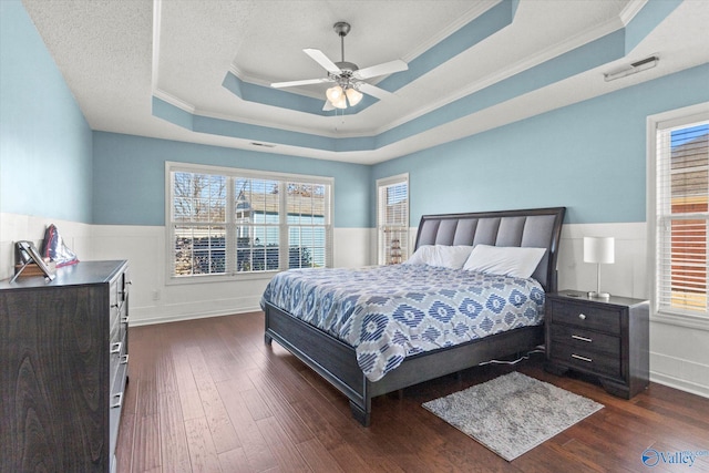 bedroom featuring crown molding, ceiling fan, a tray ceiling, a textured ceiling, and dark hardwood / wood-style flooring