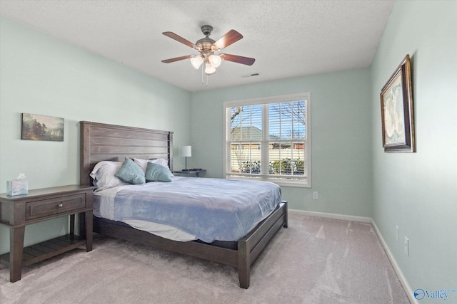 bedroom featuring light carpet, a textured ceiling, and ceiling fan