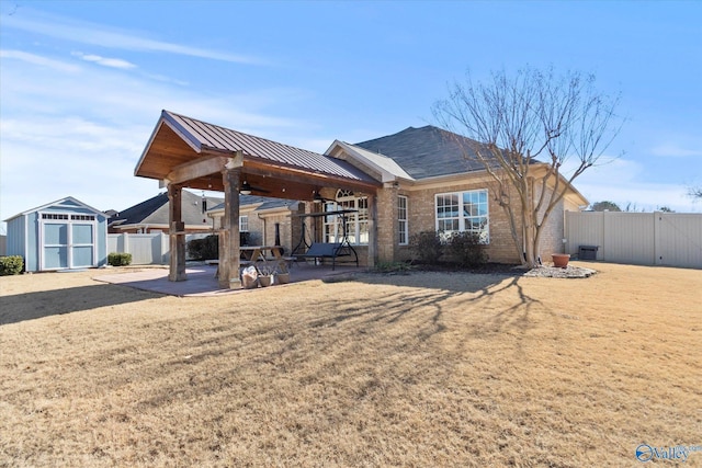 back of property with a storage shed, a lawn, and a patio area