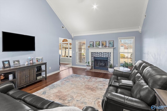 living room with crown molding, a healthy amount of sunlight, a tiled fireplace, and dark wood-type flooring