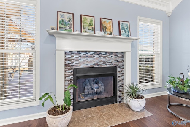 room details with a tiled fireplace, hardwood / wood-style flooring, and ornamental molding