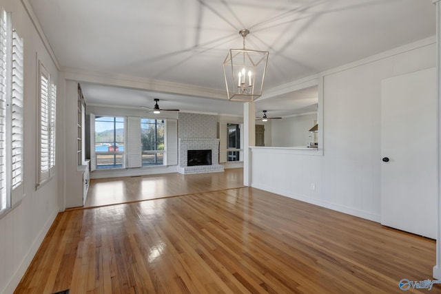 unfurnished living room featuring light wood-style flooring, a fireplace, a decorative wall, and crown molding