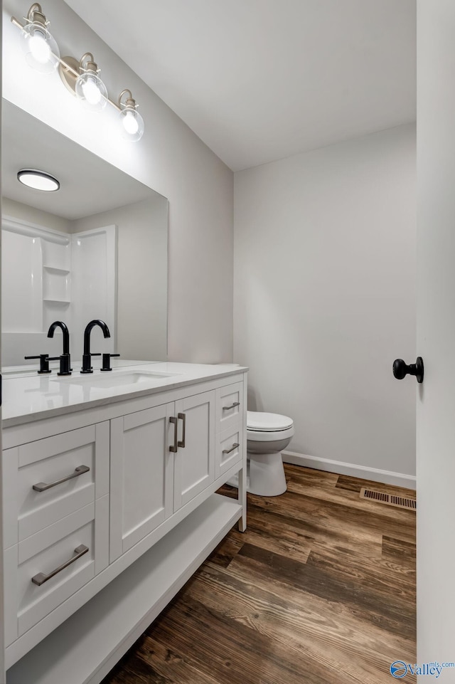 bathroom featuring toilet, wood finished floors, visible vents, vanity, and baseboards