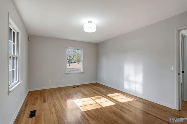 spare room featuring light wood-style floors, baseboards, and visible vents