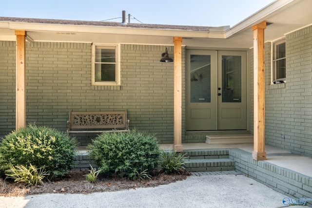 view of exterior entry with crawl space, brick siding, and french doors