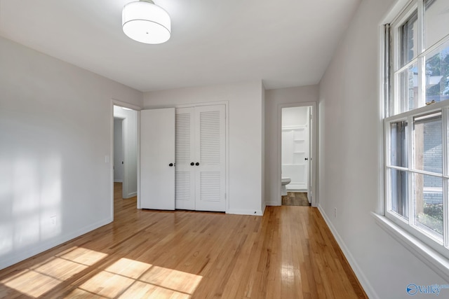 unfurnished bedroom with a closet, light wood-style flooring, and baseboards