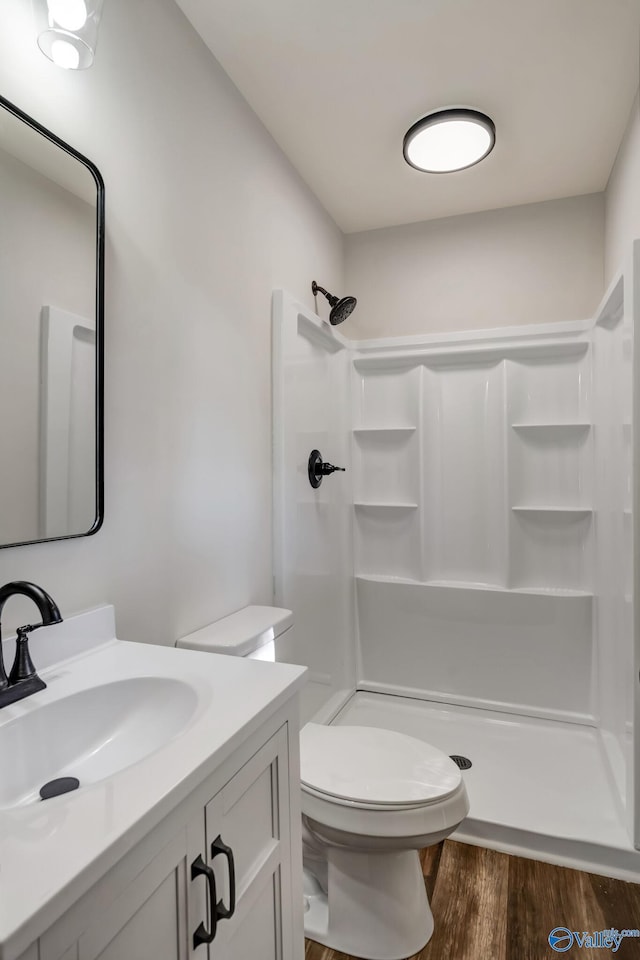 full bathroom featuring toilet, a stall shower, wood finished floors, and vanity