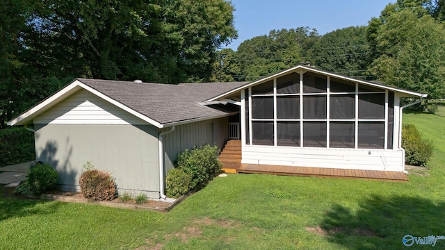 rear view of house featuring a yard, a shingled roof, and a sunroom