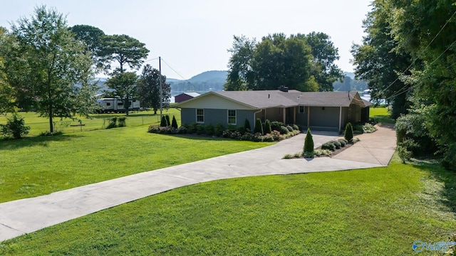 ranch-style home featuring a front yard, concrete driveway, a mountain view, and fence