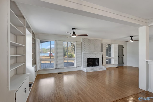 unfurnished living room featuring ceiling fan, a fireplace, wood finished floors, and visible vents