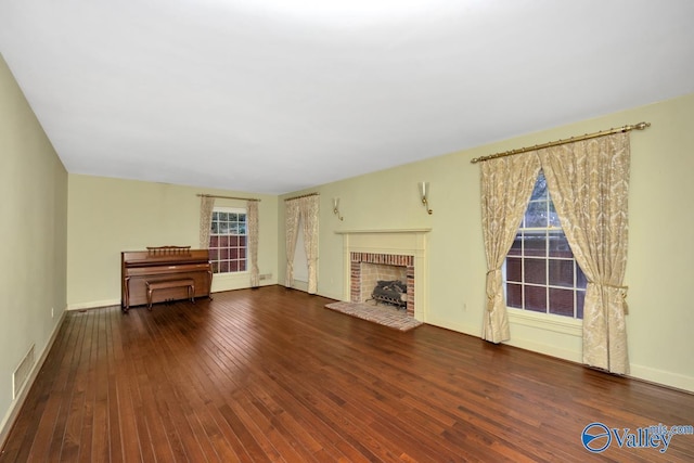 unfurnished living room featuring dark wood-type flooring and a brick fireplace