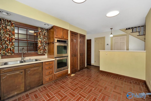 kitchen with sink, stainless steel double oven, and hanging light fixtures