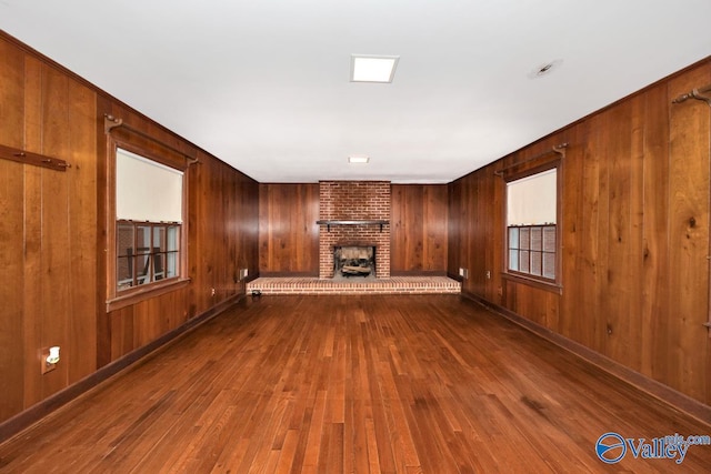 unfurnished living room with wood walls, a fireplace, and wood-type flooring