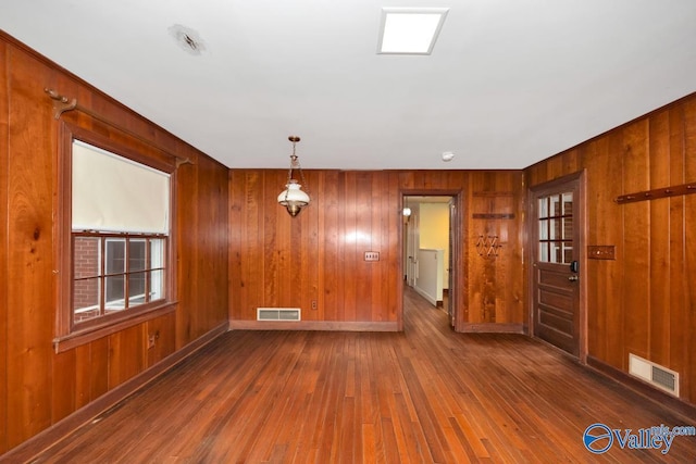 spare room featuring dark hardwood / wood-style flooring, plenty of natural light, and wood walls