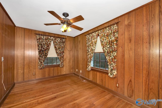 spare room featuring ceiling fan, hardwood / wood-style floors, and wood walls