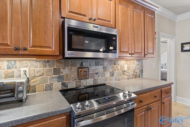 kitchen with light tile patterned floors, brown cabinetry, decorative backsplash, stainless steel appliances, and crown molding