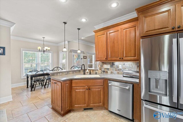 kitchen with tasteful backsplash, appliances with stainless steel finishes, brown cabinetry, a sink, and a peninsula