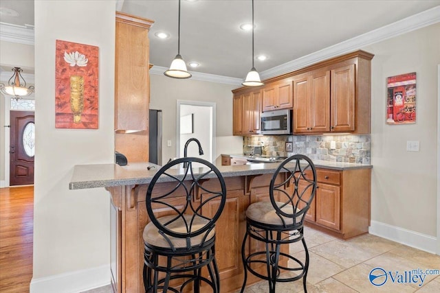 kitchen featuring decorative backsplash, stainless steel appliances, crown molding, and a kitchen breakfast bar