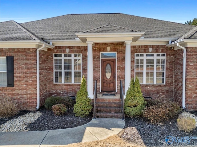 entrance to property featuring a shingled roof, crawl space, and brick siding