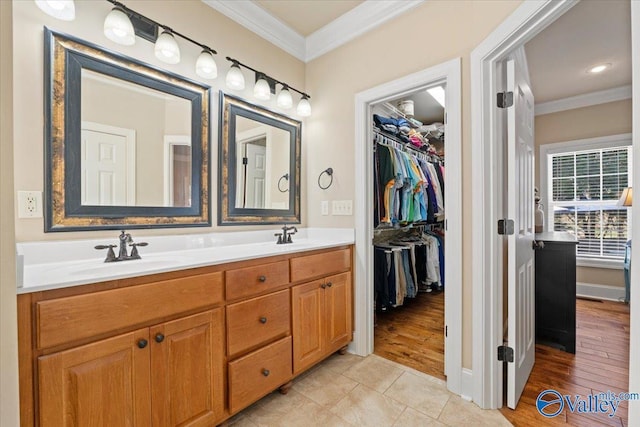 full bath with wood finished floors, a sink, a spacious closet, double vanity, and crown molding