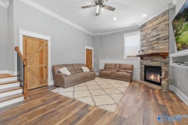 living area with ceiling fan, a fireplace, wood finished floors, stairway, and crown molding