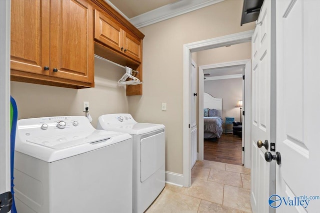 clothes washing area with cabinet space, ornamental molding, washing machine and dryer, light tile patterned flooring, and baseboards