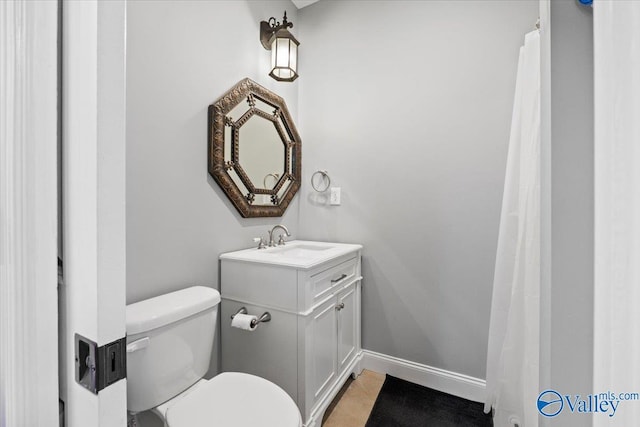 bathroom featuring tile patterned flooring, toilet, vanity, and baseboards