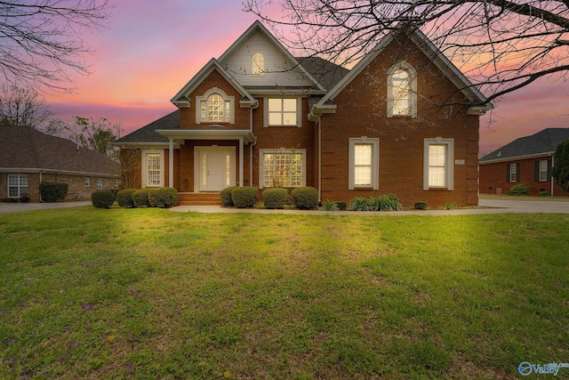 traditional-style home featuring brick siding and a front lawn
