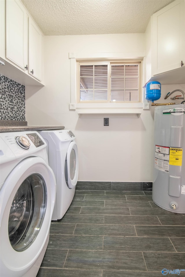 washroom featuring cabinets, a textured ceiling, water heater, and washing machine and clothes dryer