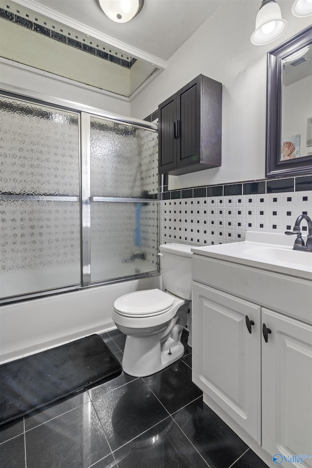 full bathroom with tile walls, enclosed tub / shower combo, vanity, toilet, and tile patterned floors