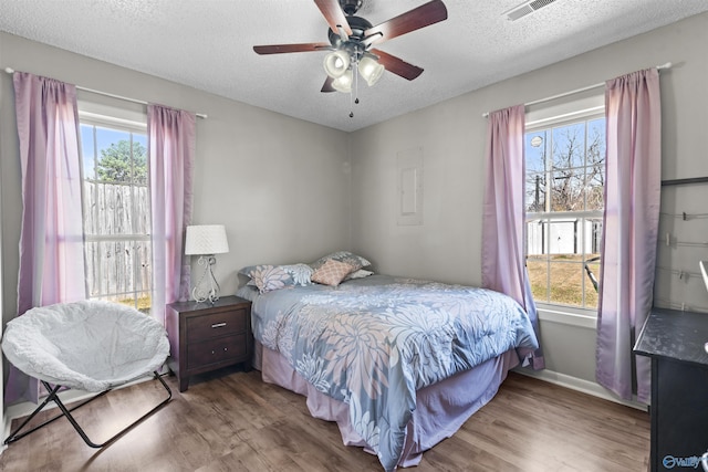 bedroom featuring ceiling fan, hardwood / wood-style floors, and a textured ceiling