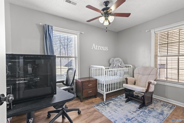 bedroom with ceiling fan, light hardwood / wood-style flooring, and a textured ceiling