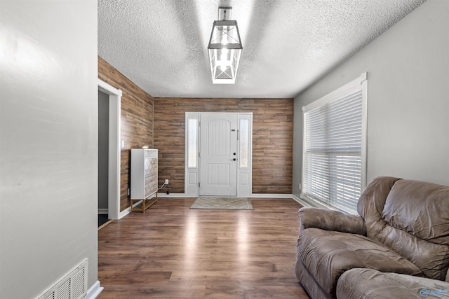 entryway featuring dark wood-type flooring, a textured ceiling, and wood walls