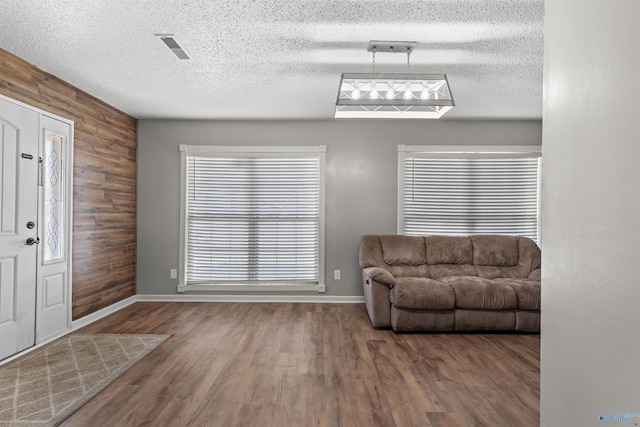 entryway with a textured ceiling, wooden walls, and wood-type flooring