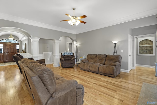living area with crown molding, ceiling fan, decorative columns, light wood-style floors, and arched walkways