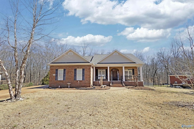 greek revival inspired property with a porch, brick siding, and a front yard