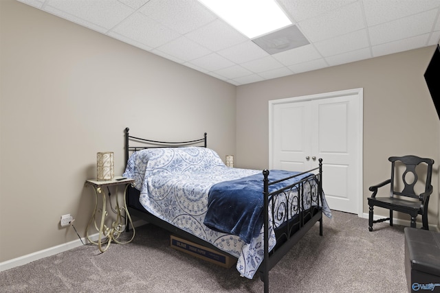 carpeted bedroom with baseboards and a paneled ceiling