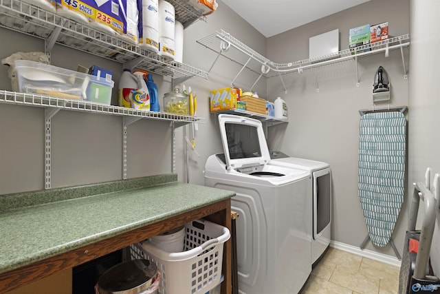 clothes washing area with baseboards, light tile patterned flooring, laundry area, and washer and clothes dryer