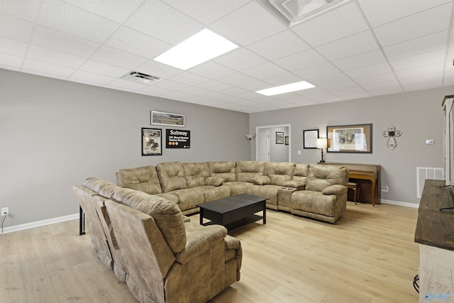 living area with visible vents, light wood-type flooring, baseboards, and a drop ceiling
