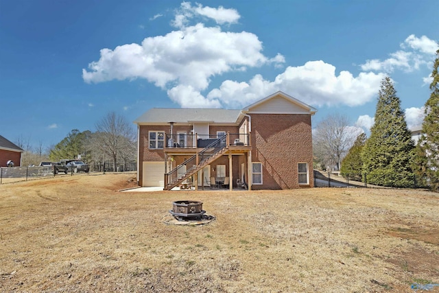 rear view of house featuring fence, a wooden deck, an outdoor fire pit, stairs, and brick siding