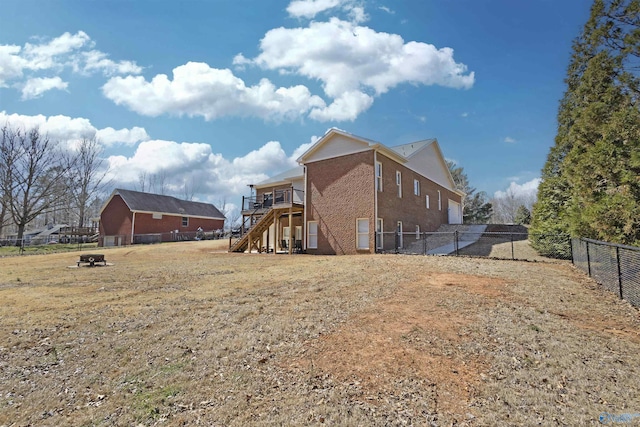 view of home's exterior with fence, a wooden deck, stairs, a garage, and brick siding